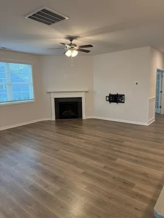 a view of an empty room with wooden floor and a fireplace