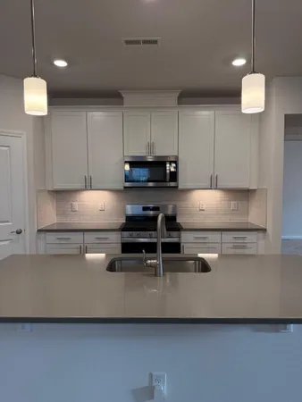 a kitchen with kitchen island a white counter top space cabinets and stainless steel appliances