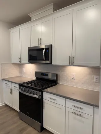 a kitchen with granite countertop white cabinets and black appliances