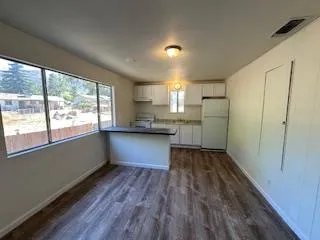 a kitchen with stainless steel appliances granite countertop a refrigerator a sink dishwasher a stove and white countertops with wooden floor