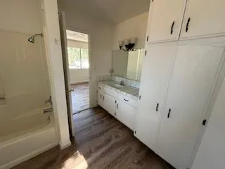 a bathroom with a granite countertop sink a mirror and a bathtub
