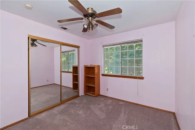 an empty room with windows closet and a ceiling fan