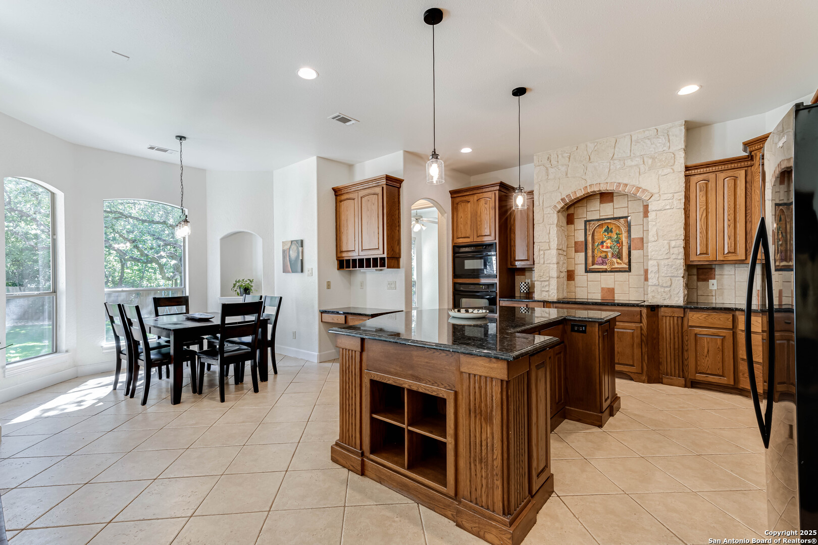 132 Long Bow Road Shavano Park, TX 78231 - Photo 17 of 50 a kitchen with stainless steel appliances granite countertop a stove top oven a sink dishwasher a dining table and chairs with wooden floor