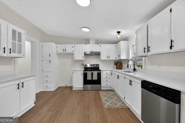 a kitchen with granite countertop white cabinets and stainless steel appliances