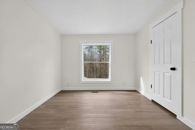 a view of an empty room with wooden floor and a window