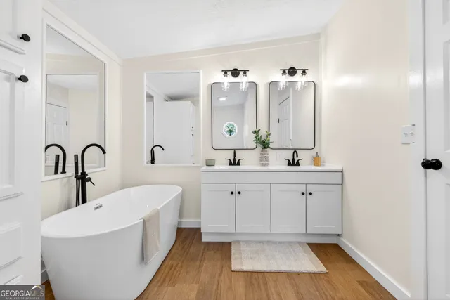 a spacious bathroom with a double vanity sink a mirror and a bathtub