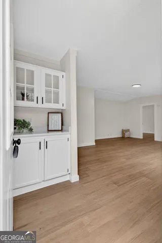 a view of a kitchen with wooden floor and white cabinets