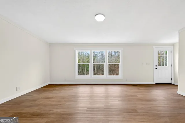 an empty room with wooden floor and windows