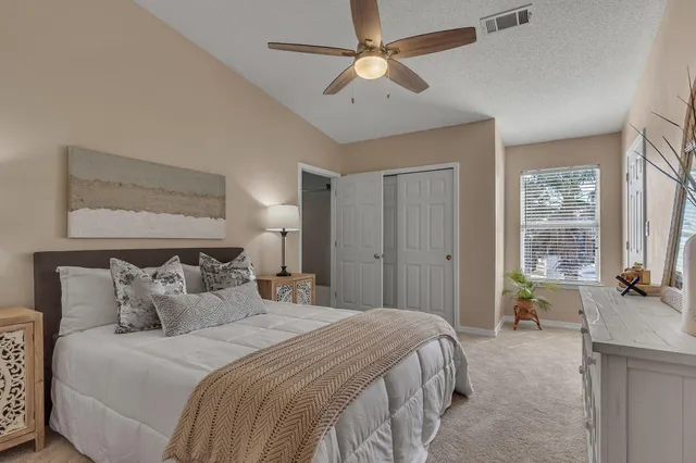 a bedroom with a bed ceiling fan and a large window