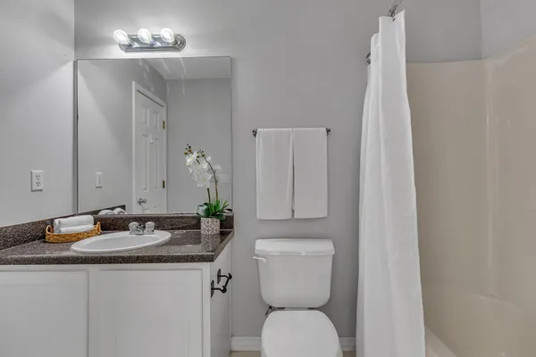 a bathroom with a granite countertop sink toilet and a mirror