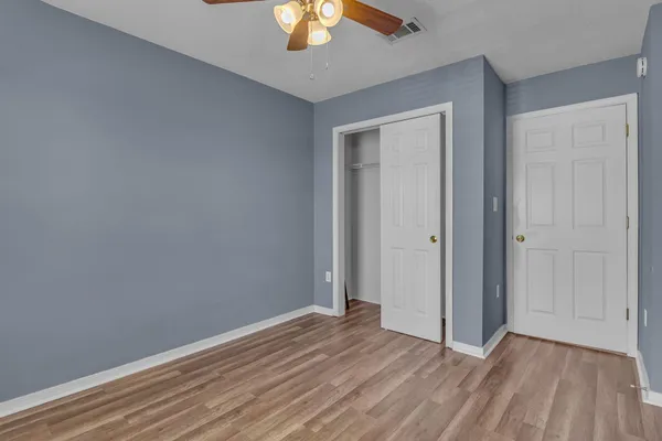 a view of an empty room with wooden floor and a chandelier fan
