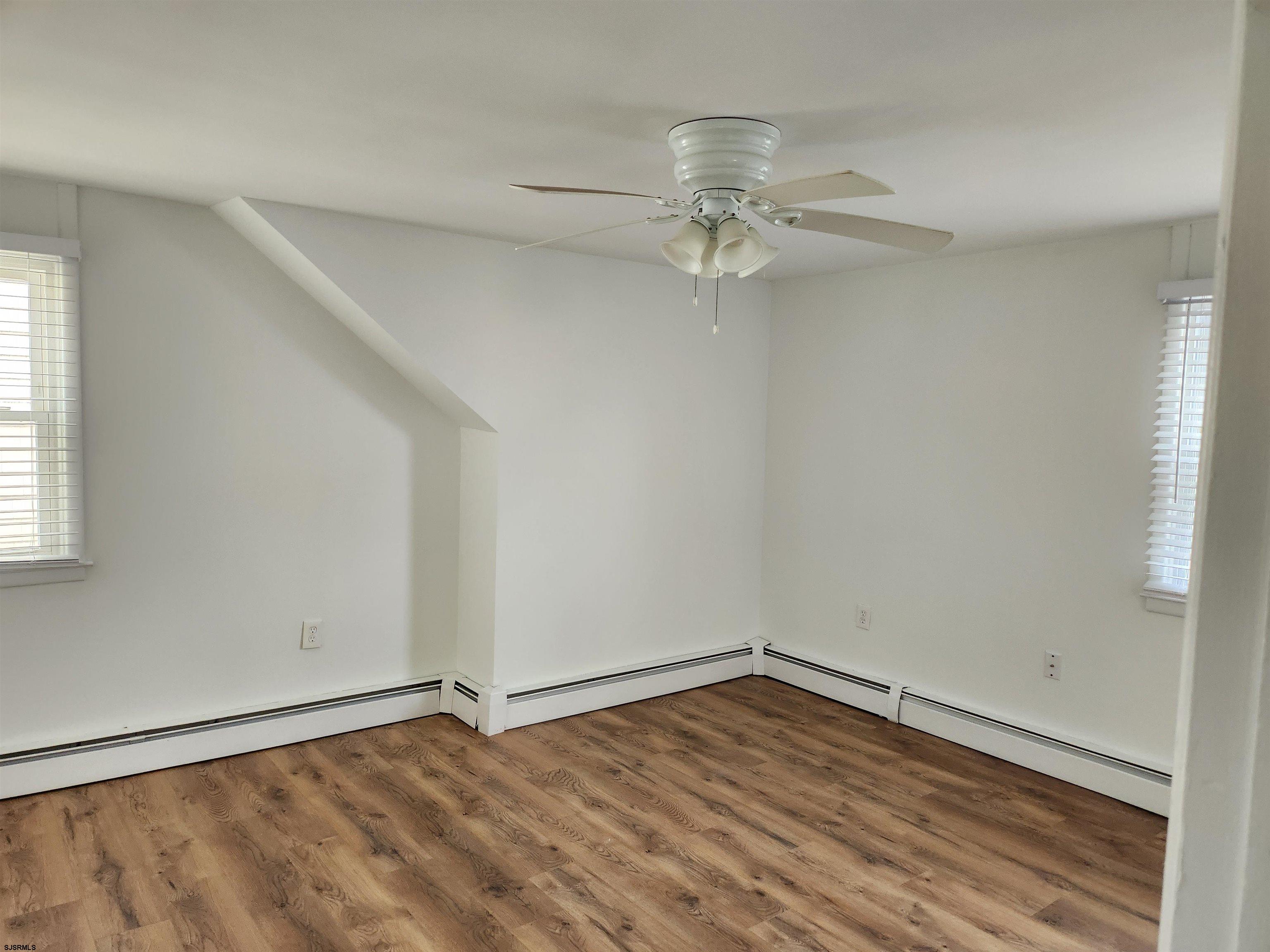 353 11th Street South, Unit 2 Brigantine, NJ 08203 - Photo 13 of 17 an empty room with wooden floor chandelier fan and windows