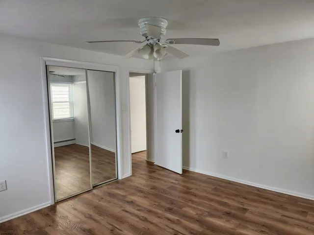 an empty room with wooden floor fan and windows