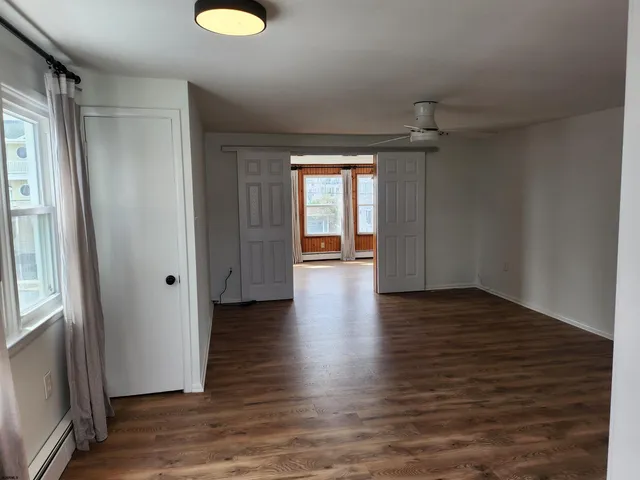 a view of an empty room with wooden floor and a window