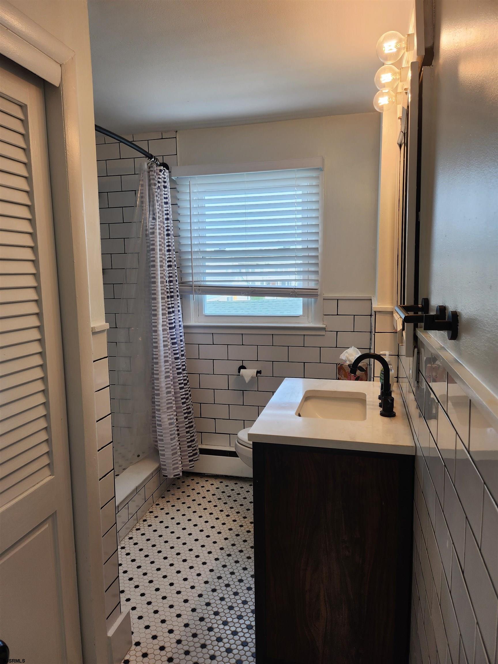 353 11th Street South, Unit 2 Brigantine, NJ 08203 - Photo 9 of 17 a bathroom with a sink a toilet a mirror and shower
