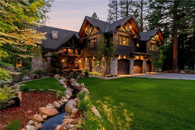 a view of a brick house with a big yard and large trees