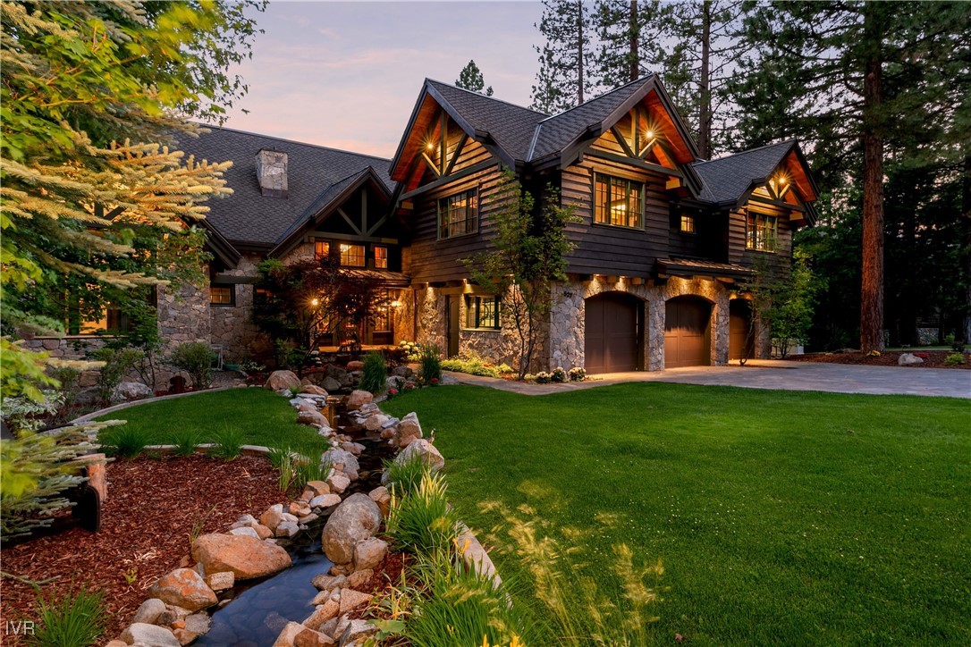 a view of a brick house with a big yard and large trees