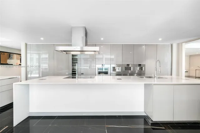 a large white kitchen with kitchen island white cabinets and stainless steel appliances