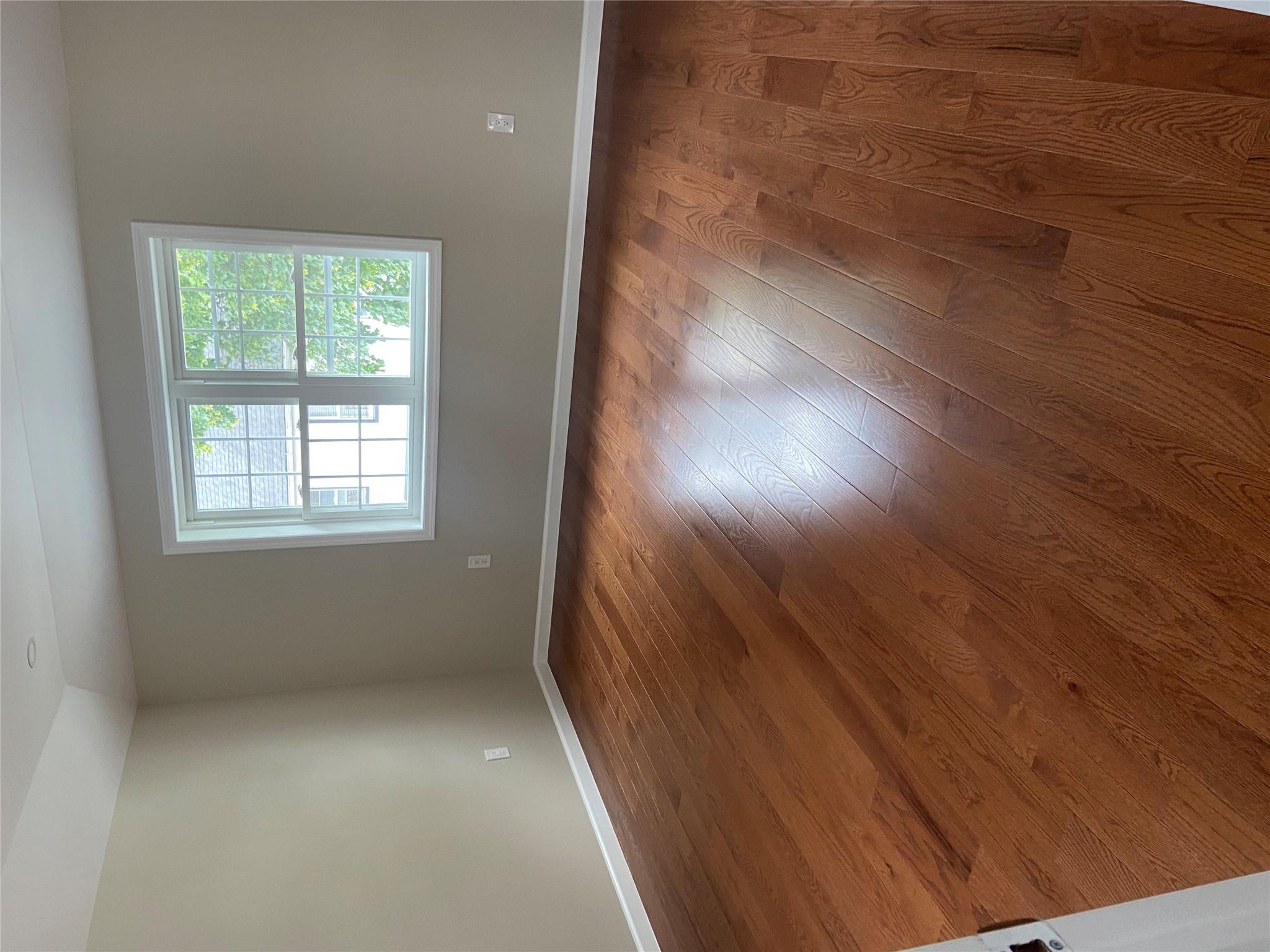 157-18 115th Road, Unit 2 FAMILY Queens, NY 11434 - Photo 31 of 36 an empty room with wooden floor and windows