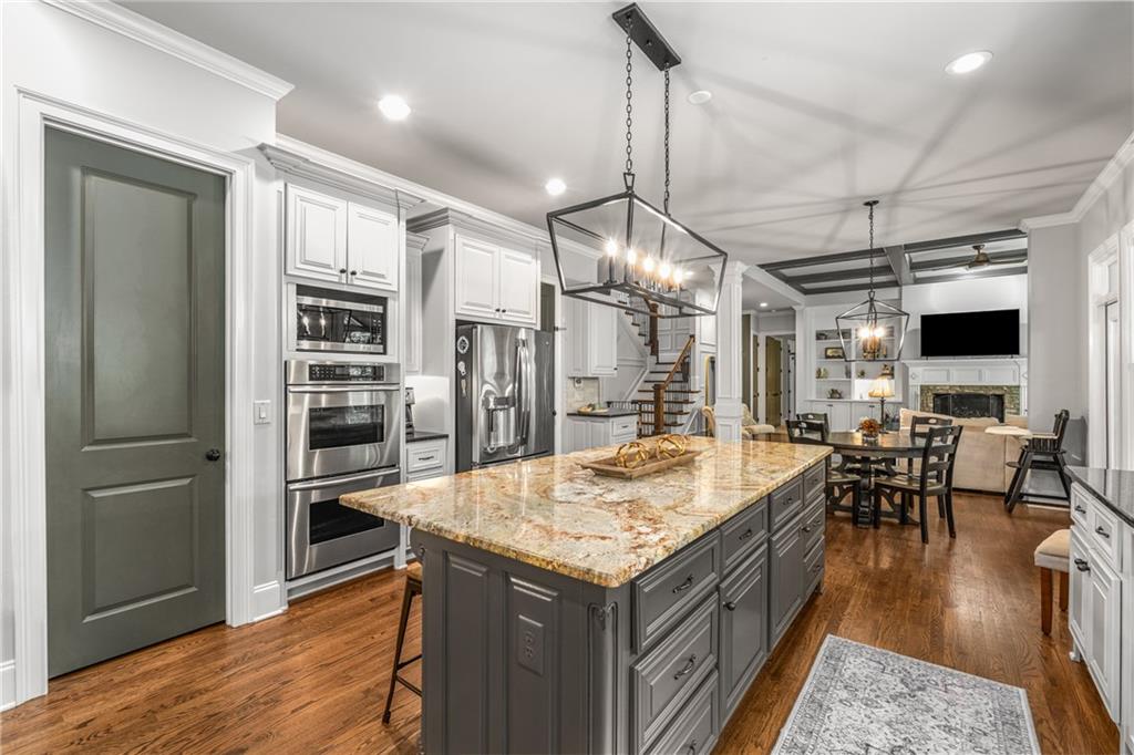 5605 Copper Creek Pass Cumming, GA 30040 - Photo 19 of 64 a kitchen with stainless steel appliances kitchen island granite countertop a table chairs and a refrigerator