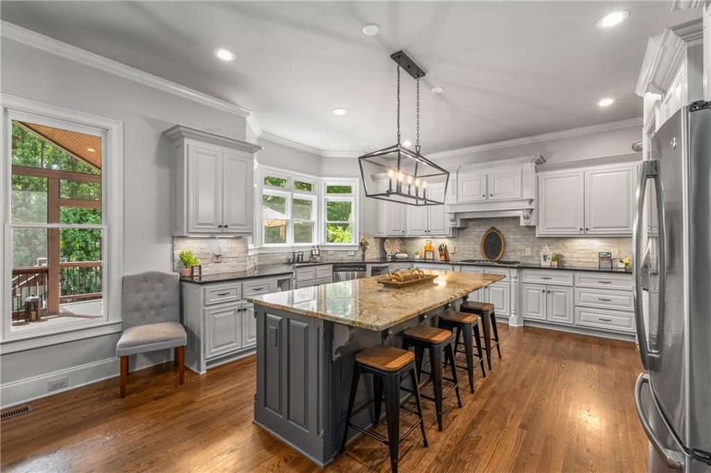 5605 Copper Creek Pass Cumming, GA 30040 - Photo 20 of 64 a kitchen with stainless steel appliances a table chairs stove and wooden floor