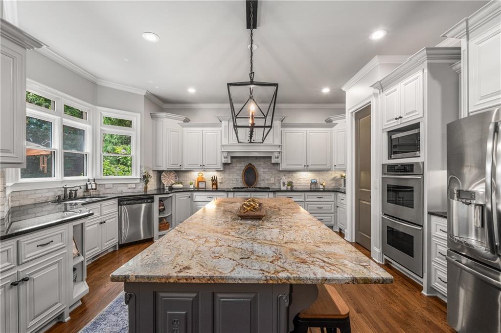 5605 Copper Creek Pass Cumming, GA 30040 - Photo 4 of 64 an open kitchen with granite countertop kitchen island wooden floor center island and stainless steel appliances