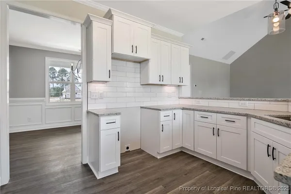 a kitchen with granite countertop white cabinets and white appliances