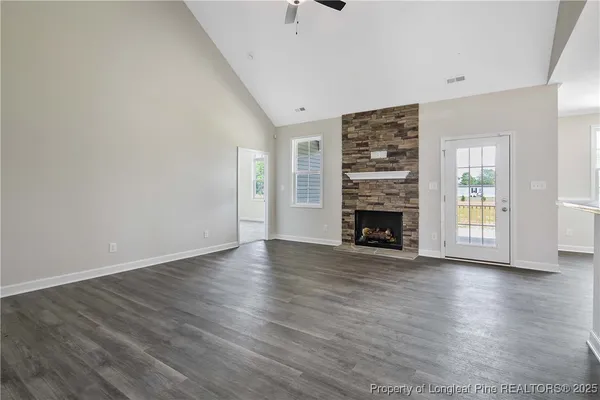 an empty room with wooden floor fireplace and windows