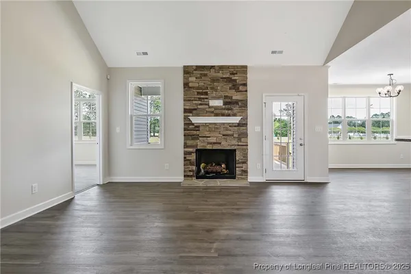 an empty room with wooden floor fireplace and windows