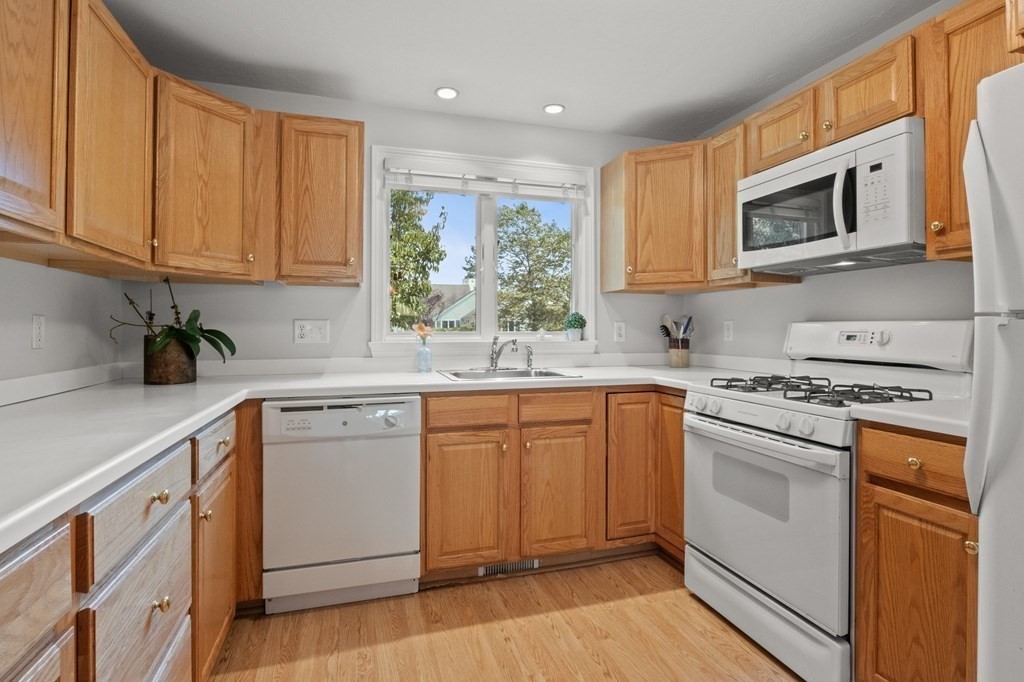 5 Woods Edge Lane, Unit 5 Mashpee, MA 02649 - Photo 7 of 29 a kitchen with stainless steel appliances granite countertop a sink a stove a microwave and cabinets