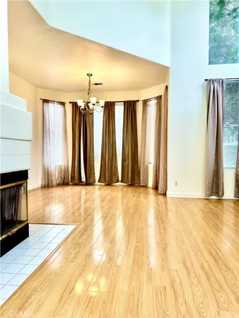 a view of an empty room with wooden floor and a fireplace