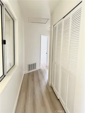 a view of a hallway with wooden floor and closet