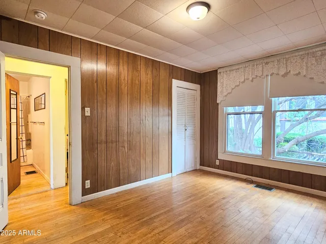 an empty room with wooden floor and windows with curtains