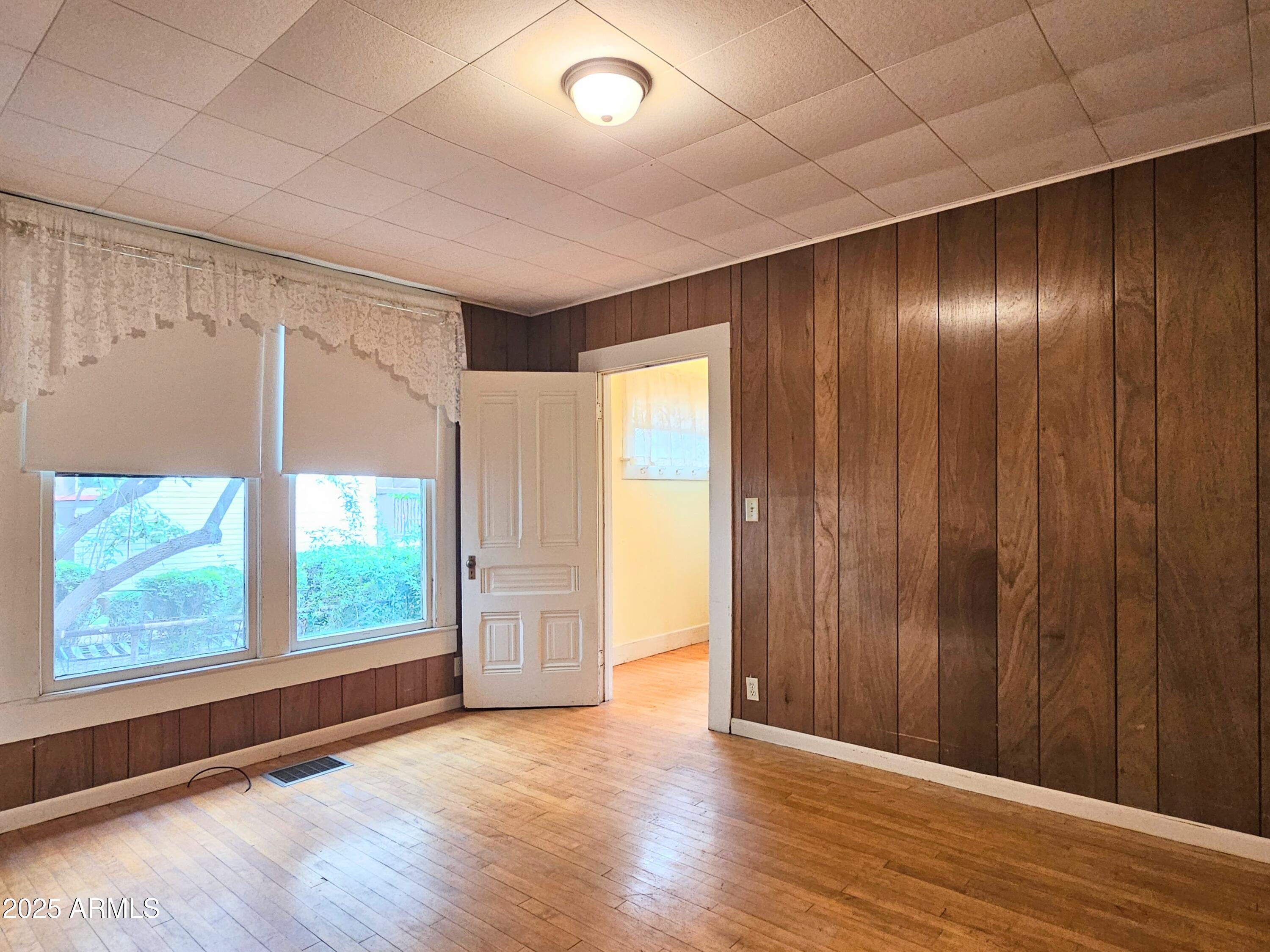 164 Quality Hill Road Bisbee, AZ 85603 - Photo 24 of 36 an empty room with wooden floor and windows with curtains