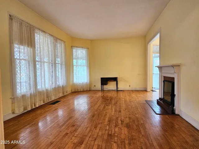 an empty room with wooden floor and fireplace