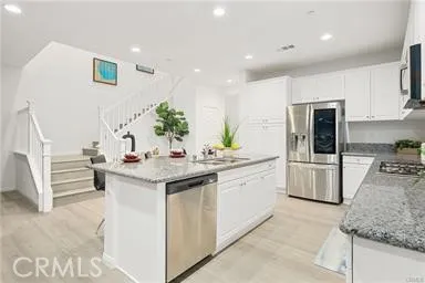 a kitchen with granite countertop a sink and white cabinets