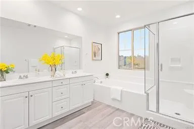 a bathroom with a double vanity sink a mirror a bathtub and next to a window