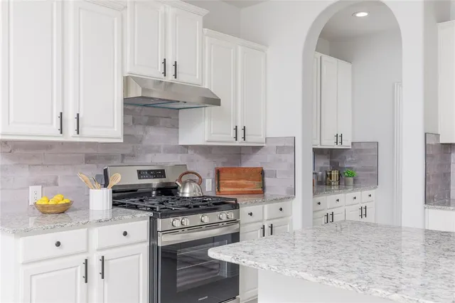 a kitchen with stainless steel appliances granite countertop a stove a sink and a white cabinets