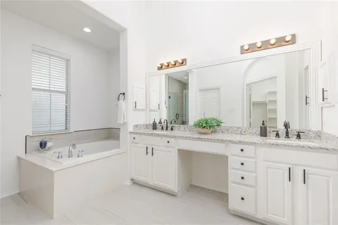 a spacious bathroom with a double vanity sink mirror and bathtub