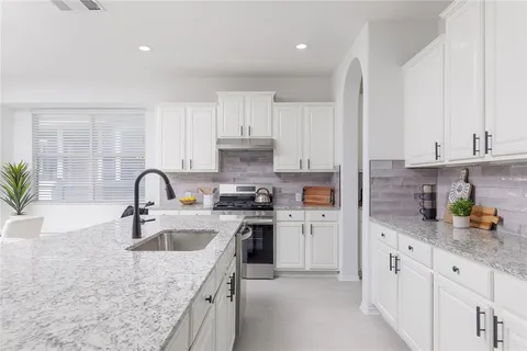 a kitchen with stainless steel appliances granite countertop lots of white cabinets a sink and dishwasher