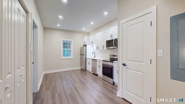 a kitchen with a refrigerator a stove top oven and wooden floor