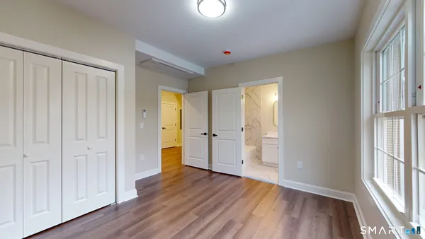 a view of an empty room with wooden floor and a window