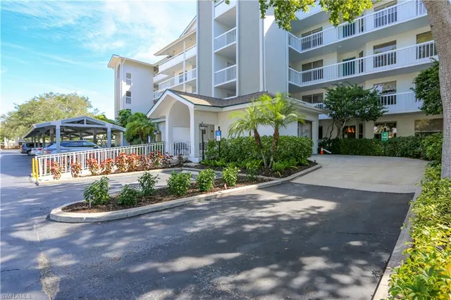 a front view of a multi story residential apartment building with yard and parking space
