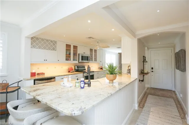 a view of a kitchen with kitchen island granite countertop a sink and cabinets