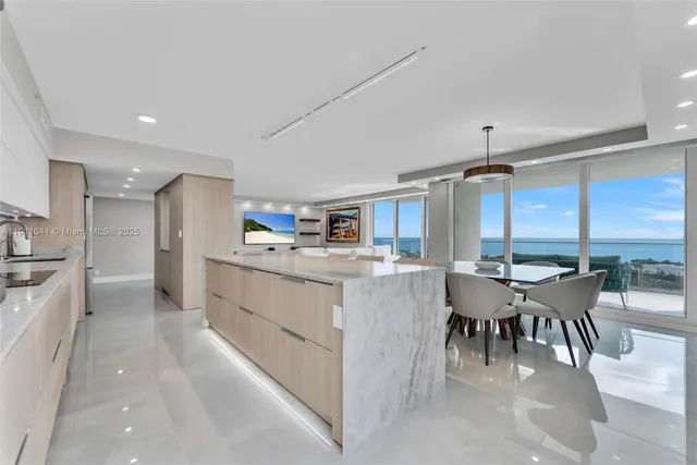 a kitchen with stainless steel appliances kitchen island granite countertop a table chairs sink and white cabinets