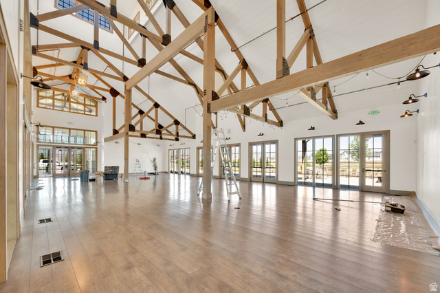 6120 North Sheps Ridge Road Eagle Mountain, UT 84005 - Photo 26 of 43 Spacious interior featuring exposed timber trusses, high vaulted ceilings, expansive wood-finish flooring, multiple sets of French doors, and decorative wall-mounted lighting fixtures