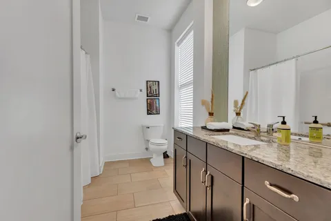 a bathroom with a granite countertop sink mirror and a toilet