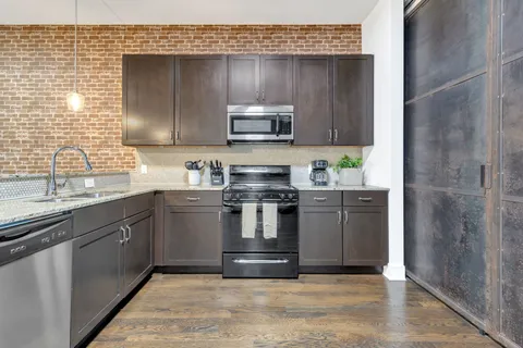a kitchen with stainless steel appliances granite countertop a stove a sink and a microwave
