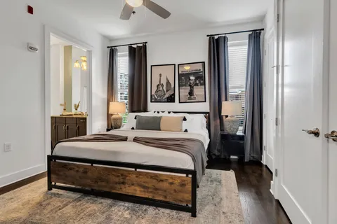 a bedroom with a bed painting on wall and a large window