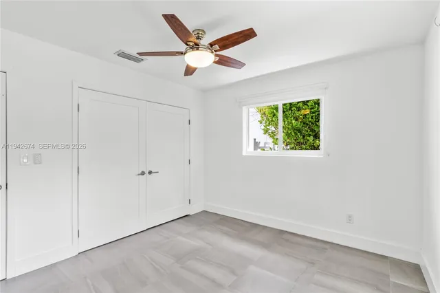 an empty room with window and ceiling fan